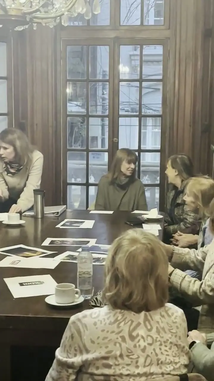 El grupo del Club Social conversando alrededor de la mesa, junto a los ventanales del salón