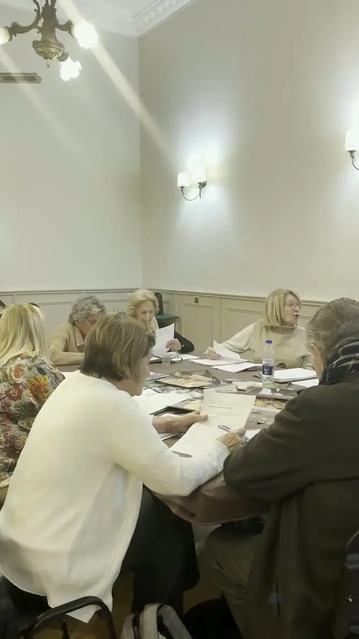 El grupo del Taller de Memoria trabajando con sus carpetas en el salón, bajo la araña de cristal